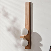 Oak tall Eveline double wall sconce with two white glass globe shades unlit on white plaster wall