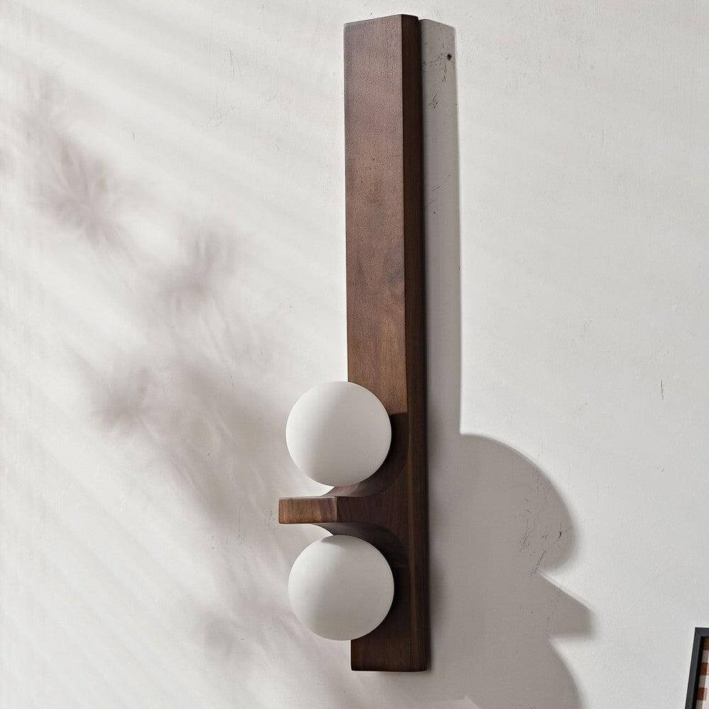 Walnut tall Eveline double wall sconce with two white glass globe shades unlit on white plaster wall