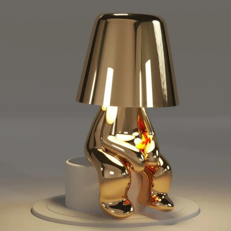 Gold RayDudes sunset lamp in awaited sitting pose on white display stand