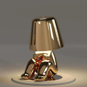 Gold RayDudes sunset lamp in baffled confounded crouching pose on white stand