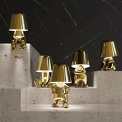 Five gold RayDudes sculptural lamps in different poses arranged on marble staircase steps
