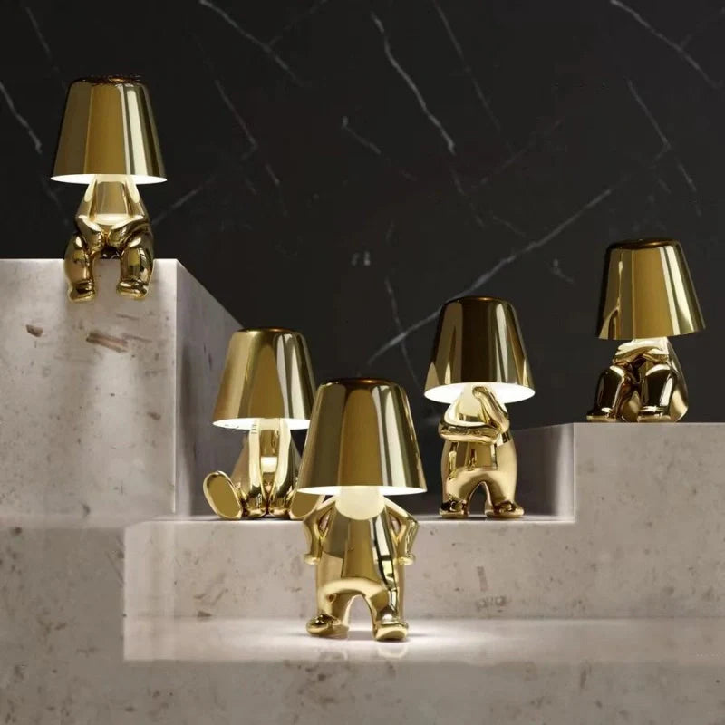 Five gold RayDudes sculptural lamps in different poses arranged on marble staircase steps