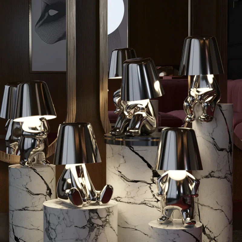 Five silver RayDudes sculptural lamps in different poses arranged on marble staircase steps