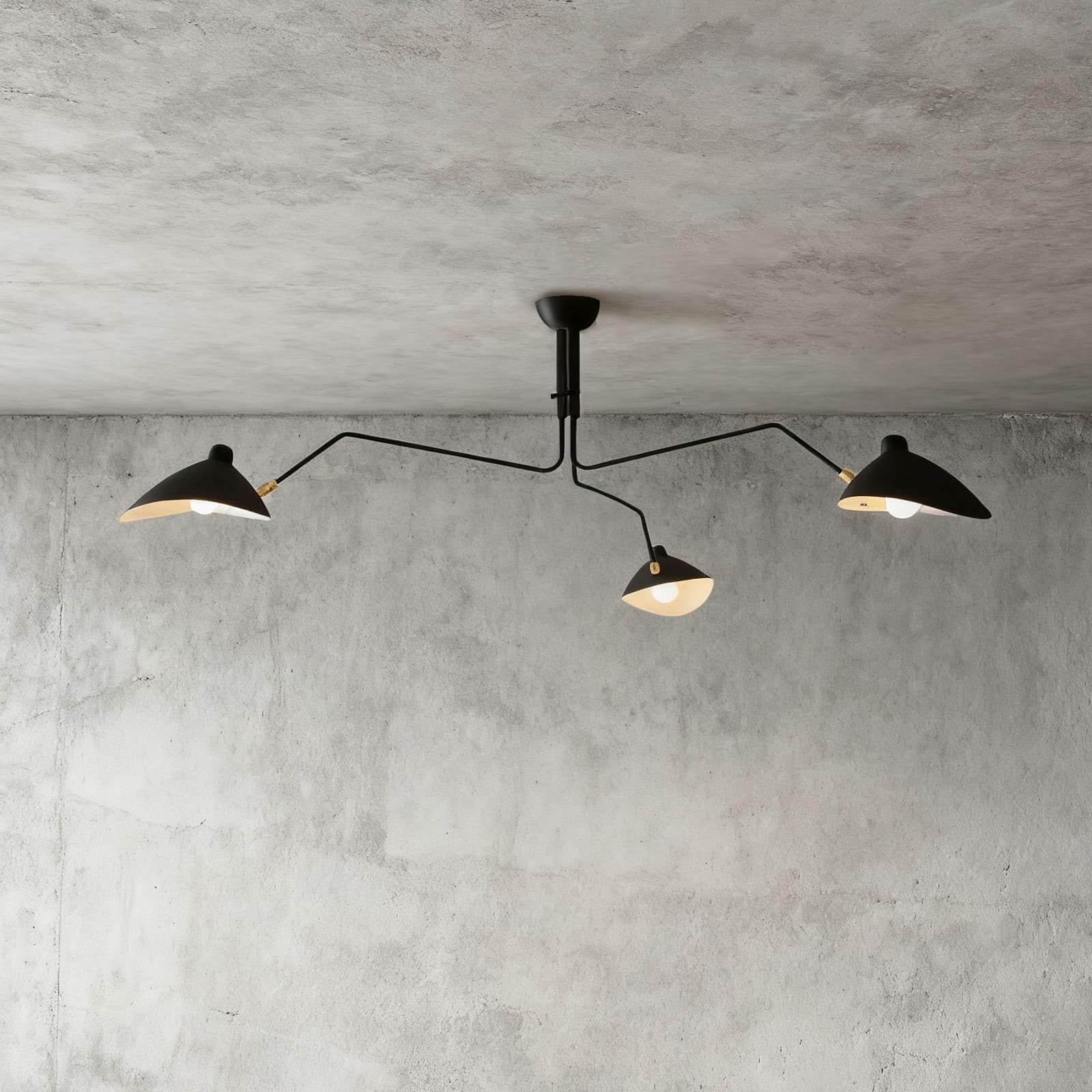 Black 3-arm Serge Mouille inspired ceiling light with brass joints on concrete ceiling product shot