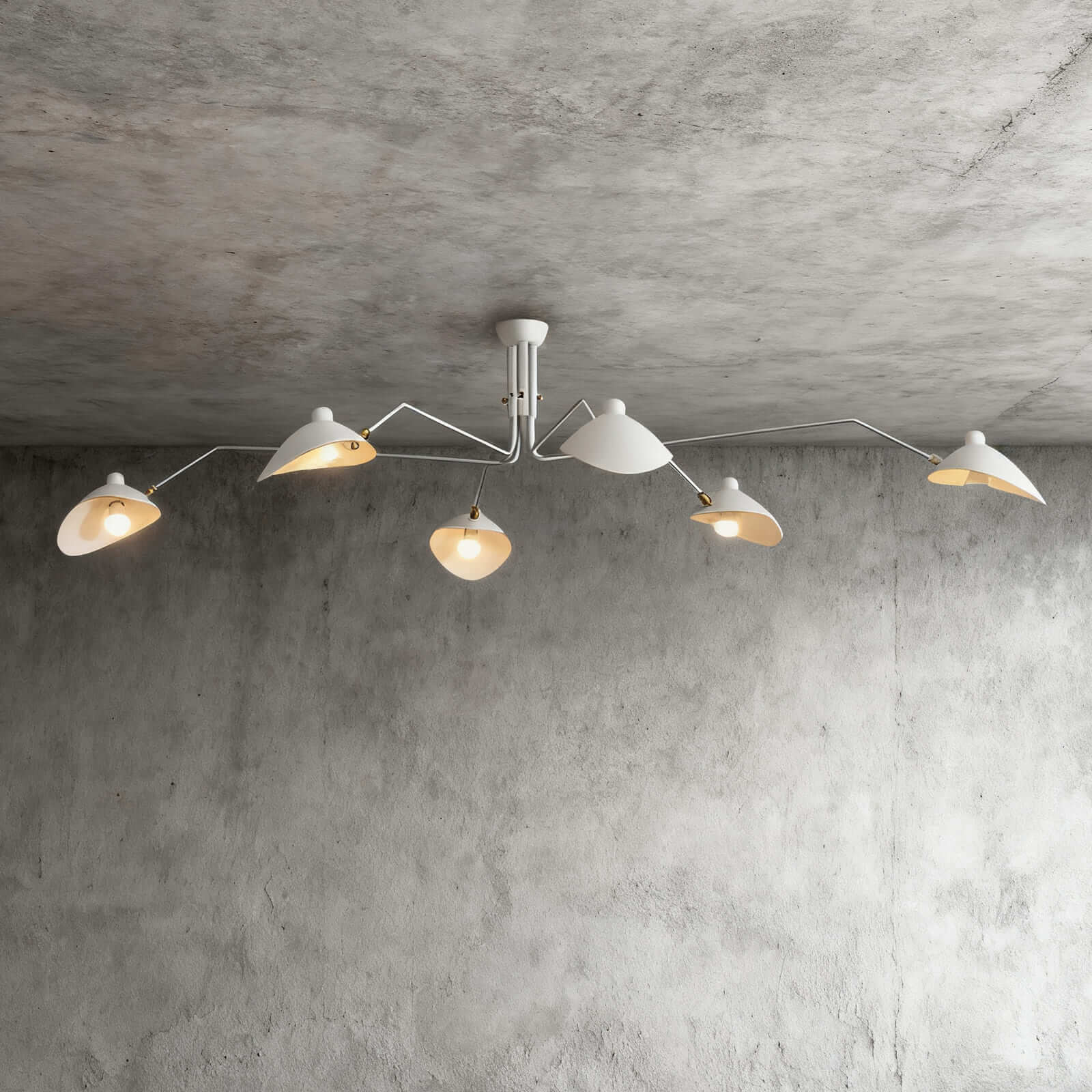 White 6-arm Serge Mouille inspired ceiling light with brass joints spanning wide on concrete ceiling product shot